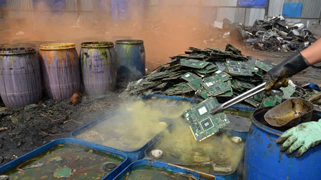 Acid bath trays and stripped GPU boards in a toxic scrap yard